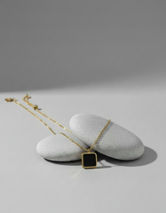 Necklace with a square pendant on a gray surface