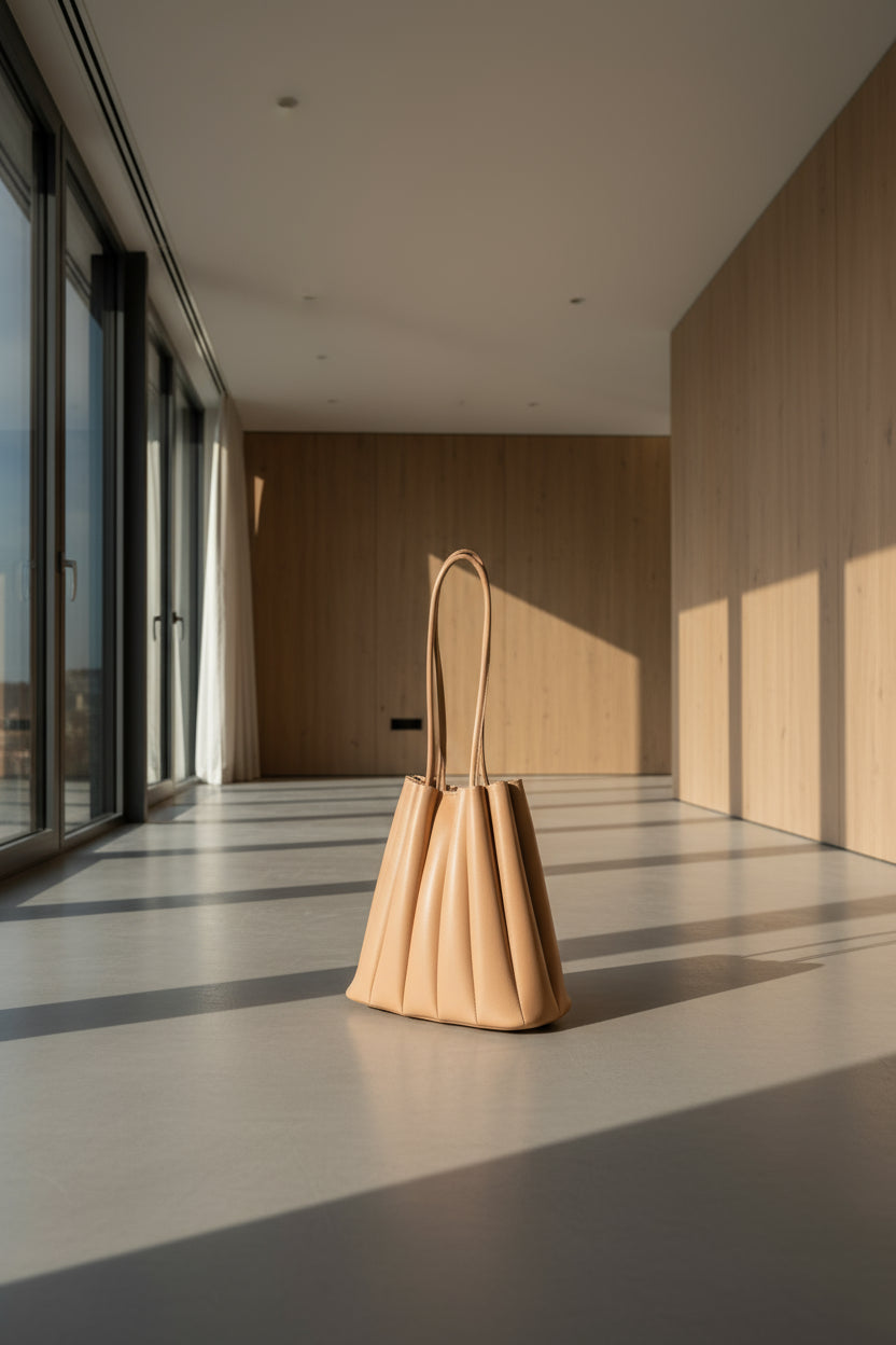 Beige handbag with pleated design on a white background